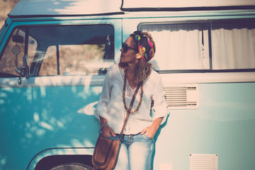Cute stylish trendy adult caucasian woman stand up with blue vintage van in background - concept of travel and fashion driver lifestyle - alternative people with vehicle