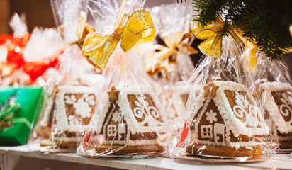 Christmas handmade gingerbread cookies on wooden shelf, small house shaped cake, packed with red and gold bow