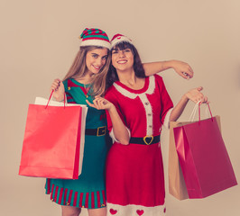Two pretty happy women in santa hat and funny christmas clothes shopping christmas gifts