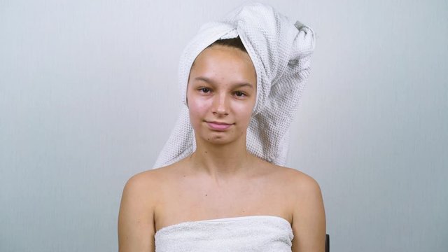 Pretty girl wrapped in bath towels applying face cream