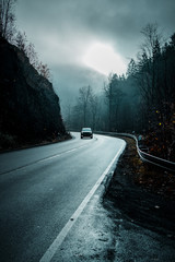 Road trip with a car driving though the moody winter mountains and heavy dark fog and mist....