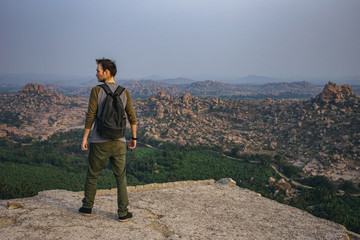 tourist guy standing on the edge of a hill. Beautiful view of the amazing Hampi's ruins from Matanga hill. Karnataka, India