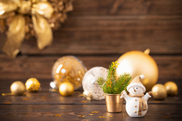 Christmas golden decorations and snowman on dark wooden backgrou