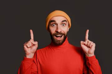 Amazed man face pointing upwards showing to a place above his head, smiling with an excited and...