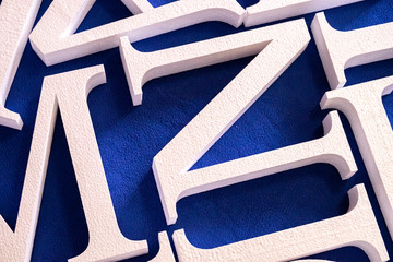 white letters cut out of foam without painting on a blue background. blank for decoration, logo...
