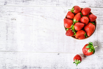 Ripe strawberries forest fruits in wooden bowl on white table. Fresh strawberry top view.