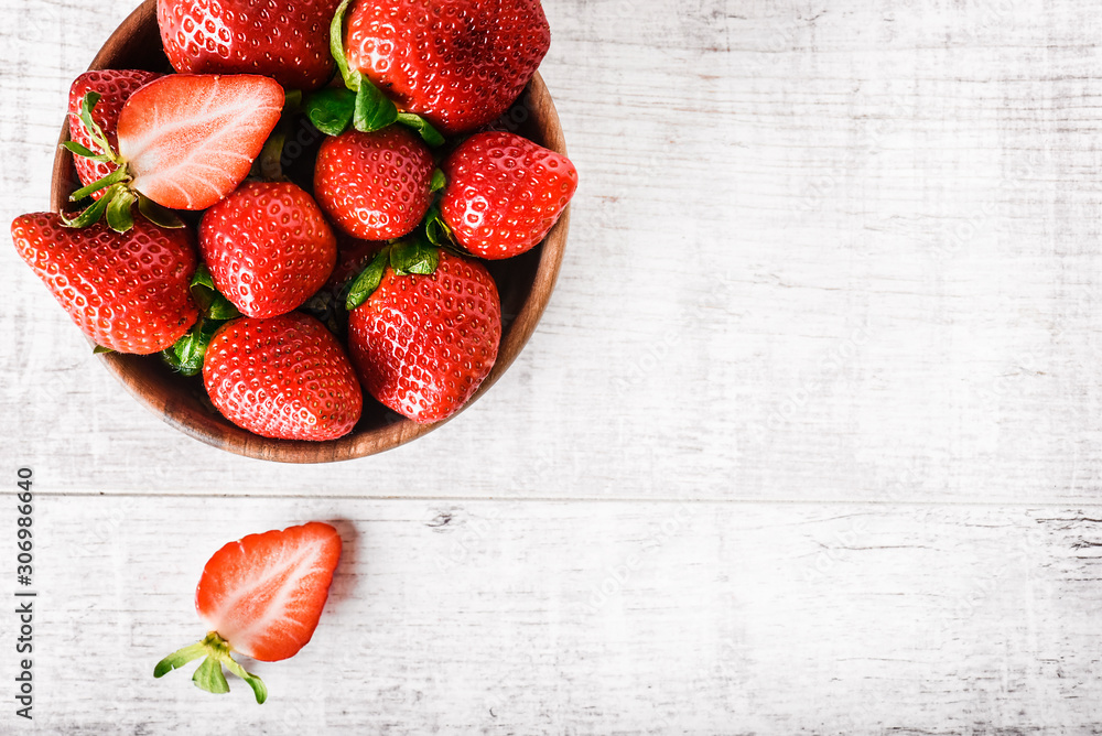 Wall mural ripe strawberries forest fruits in wooden bowl on white table. fresh strawberry top view.