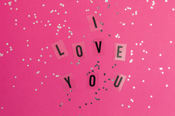 I Love you text on Pink background with multicolored confetti. Flat lay style. Top view