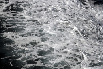 Fototapeta na wymiar Weisser Schaum auf der Wasseroberfläche im Meer. Gischt am Ozean bei einer Fahrt mit dem Schiff. Wasser in Bewegung. Schäumende Oberfläche