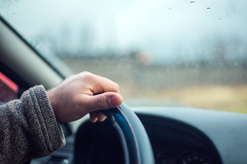 Selective focus man's hand on steering wheel, driving a car