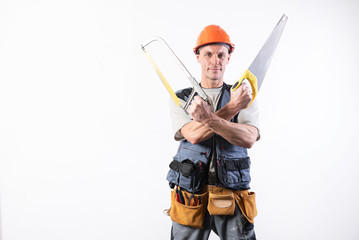 A builder with hacksaw in a helmet, smiling. On a light background.