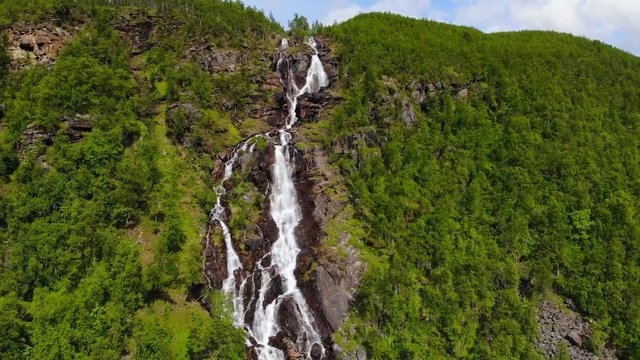 Aerial, drone shot, towards a narrow waterfall, in the Steindalen valley, on a sunny, summer day, in Lyngen alps, Troms, Norway