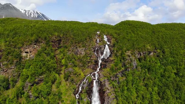 Aerial, reverse, drone shot, of a waterfall, in the Steindalen valley, on a sunny, summer day, in Lyngen alps, Troms, Norway