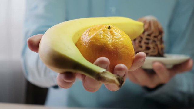A man chooses fresh fruit instead of a cake in favor of a healthy diet. concept: Healthy food, proper nutrition, fitness, weight loss, weight loss