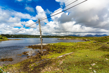 Old and inclined light post with electric wires on the shore of the Adbear salt lake, sunny day...