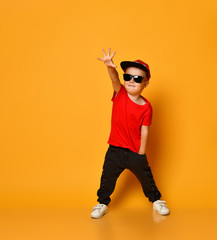 Young guy boy in a red T-shirt and dark pants, white sneakers and a funny cap posing on a free copy...
