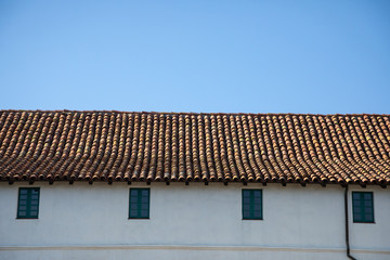 Red tile roof on a stucco building, with a blue sky background