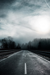 Low hanging clouds and fog in the mountains top of pine trees on a moody dark winter day with contrastful cold color tones. National Park Harz Mountains in Germany