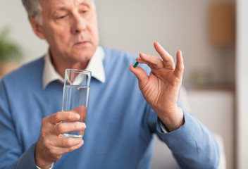 Elderly Man Holding A Pill And Glass Of Water Indoor