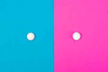 Two white pills on blue and pink backgrounds. Separation into two equal sides. A place for copyspace. Medical concept.