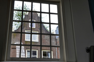 Amsterdam, the Netherlands. August 2019. Seen from inside the church of the city beguinage, through a large window one recognizes the typical facades of Dutch houses.
