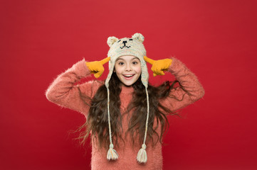 Winter outfit. Little kid wear knitted hat. Stay warm. Little girl winter fashion accessory. Small child long hair wear hat red background. Cute model enjoy winter style. Teddy bear. Being cute bear