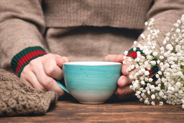Woman in warm sweater drinking a hot tea close up background.