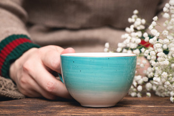 Woman in warm sweater drinking a hot tea close up background.