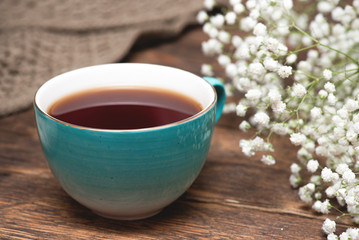 Tea cup cup and gypsophila flowers on wooden table background close up.