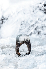 Wooden jewlery which is ring with resin top on the backghround made with ice