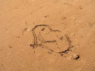 Smiling heart drawn on the wet sand.