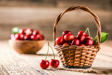 Beautiful cherries in wooden wicker basket on table. Bowl full of cherry in background.