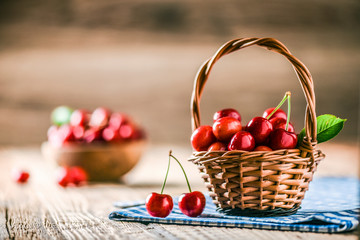 Beautiful cherries in wooden wicker basket on table. Bowl full of cherry in background.