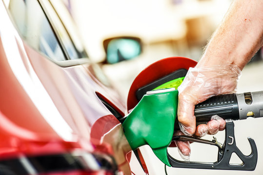 Man At Gas Station Refueling Gasoline Or Diesel. Hand With Clear Gloves Holding Fuel Pump Or Pistol.