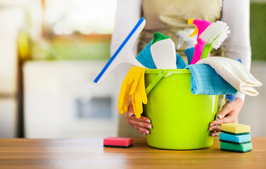 Woman holding cleaning items in plastic bucket. Kitchen service washing concept.