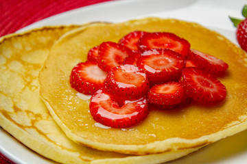 Detail of strawberries and pancakes with Syrup  on the white plate