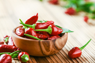 Hot chili peppers in bowl on rustic old table. Red pepper close up or detail.