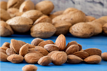 Almond. Almond nuts  peeled and in shell on a wooden  blue background Macro.
