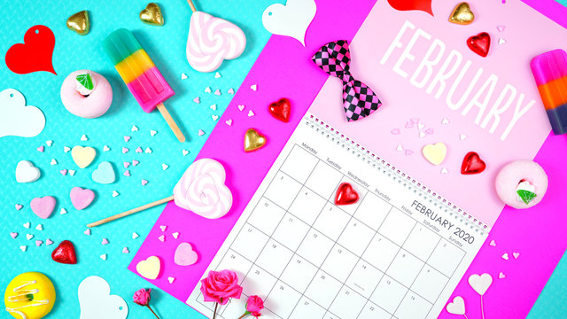 On-trend 2020 calendar page for the month of February modern flat lay with seasonal food, candy and colorful decorations in popular pastel colors. Vertical. One of a series for 12 months of the year.