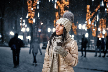 Lady in jacket, knitted hat, scarf, gloves with coffee cup