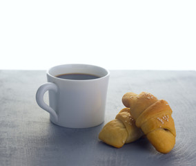  white cup with coffee and homemade pasties on a gray wooden tabletop and white background