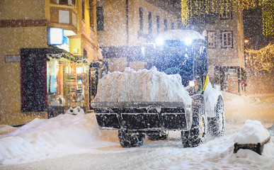 Highway maintenance heavy truck cleaning road during blizzard or snowstorm in evening, winter...