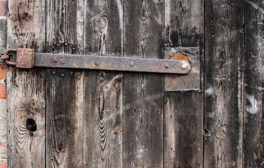 Part of old wooden weathered  board door with iron bar and padlock 