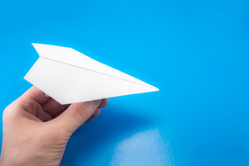 paper airplane made of white paper in the hand on a light blue background, copy space, mock up