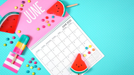 On-trend 2020 calendar page for the month of June modern flat lay with seasonal food, candy and colorful decorations in popular pastel colors. Copy space. One of a series for 12 months of the year.