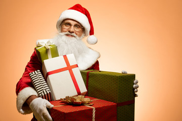 Senior man in red Santa Claus costume holding gift boxes
