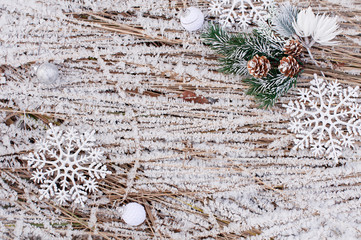 Christmas outdoor background with frozen grass with ice crystals and with fir cones and large shiny toys snowflakes