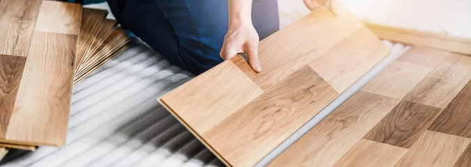 Foto op Aluminium Worker hands installing timber laminate floor. Wooden floors house renovation with measure items. © Milan