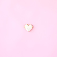 Heart shaped cookie on pink background.