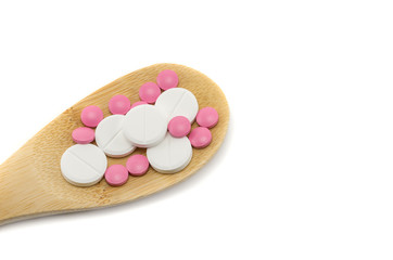 Obraz na płótnie Canvas multi-colored tablets in a wooden spoon on a white background isolated, blank, mock up, copy space
